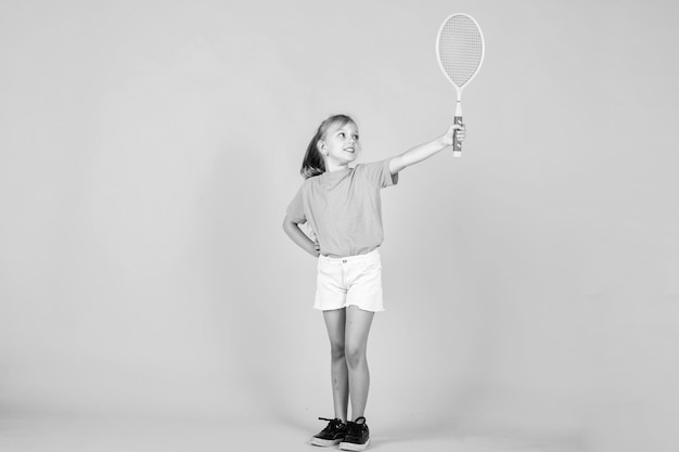 Bambino carino giocare a tennis o badminton stile di vita attivo pieno di energia bella ragazza adolescente con racchetta da tennis sport moda stile fitness e salute infanzia felice Lo sport è la nostra vita