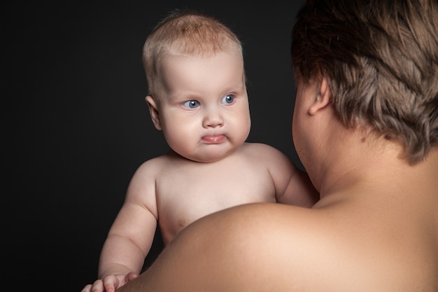 Bambino carino guardando oltre la spalla del padre, isolato su nero