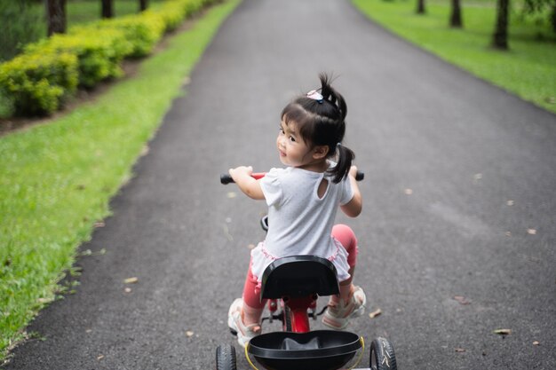 Bambino carino in bicicletta in giardino