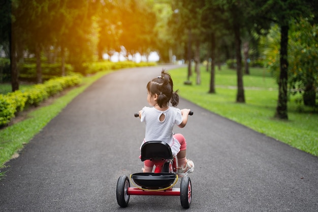 Bambino carino in bicicletta in giardino