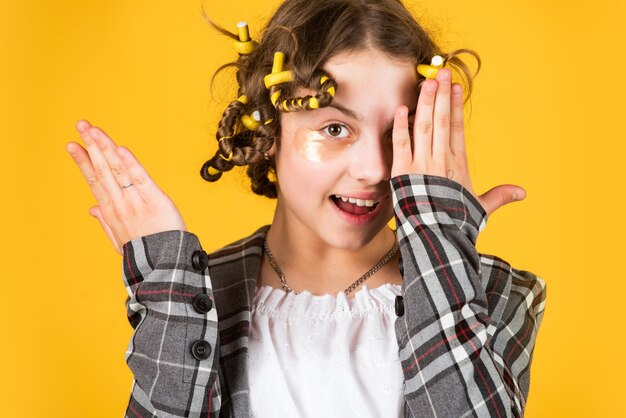 Bambino carino in piedi con toppe sotto gli occhi Concetto di modello di moda bambino Bambino che fa acconciatura bambina felice con bigodini in maschera di tessuto per capelli sotto gli occhi per la bellezza come ha funzionato bene