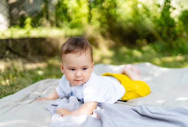 Bambino carino sdraiato su una coperta sull'erba all'aperto in estate Concetto di infanzia felice e sano