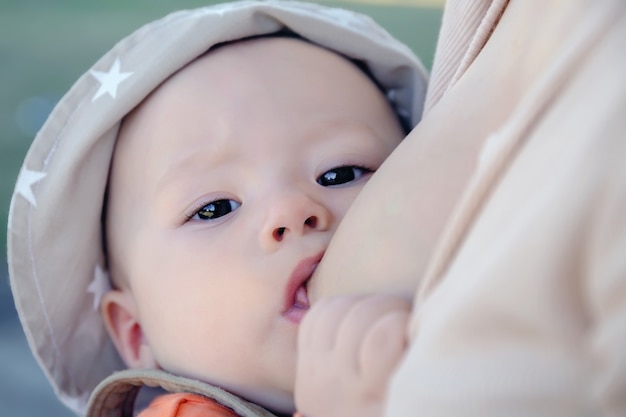 Bambino carino succhia il seno della madre da vicino