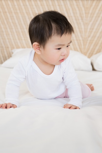 Bambino carino sul letto guardando in basso