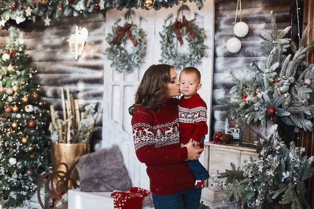 Bambino carino sulle mani della sua bellissima madre all'interno di Natale