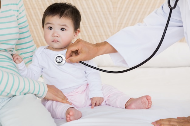 Bambino carino visitato dal medico sul letto