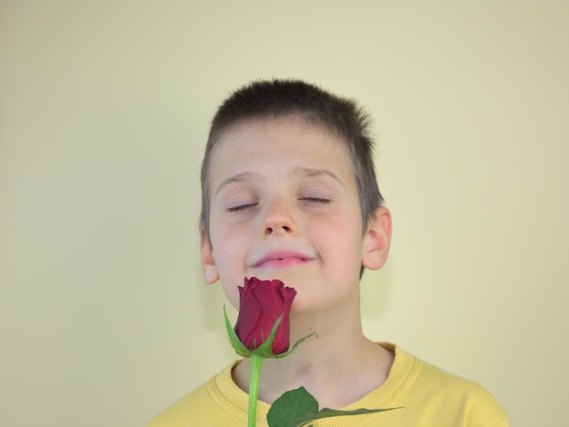 Bambino caucasico felice che sente l'odore dell'occhio della strega della rosa rossa chiuso