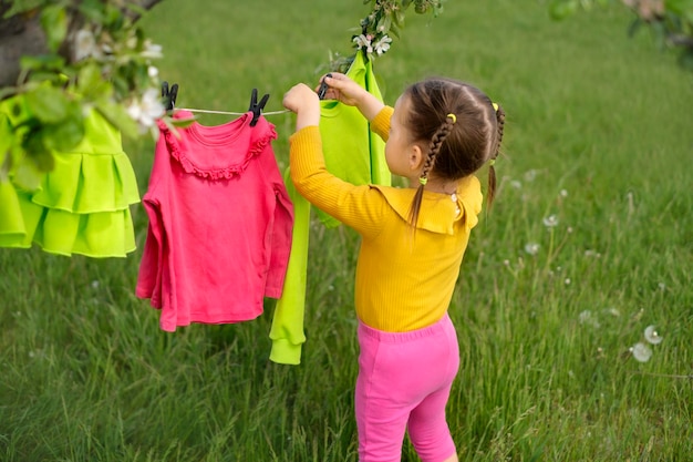 Bambino che appende i vestiti bagnati dopo il bucato su una corda da bucato con le mollette