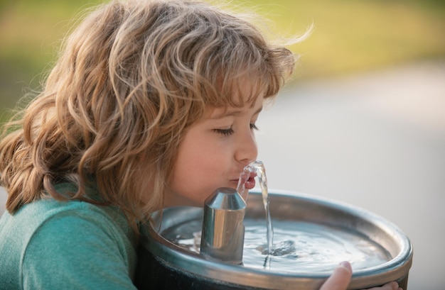 Bambino che beve acqua da una fontana d'acqua all'aperto