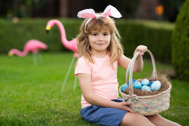 Bambino che caccia le uova di Pasqua Ragazzo carino in costume da coniglio con orecchie da coniglio che caccia all'uovo di Pasqua di Pasqua