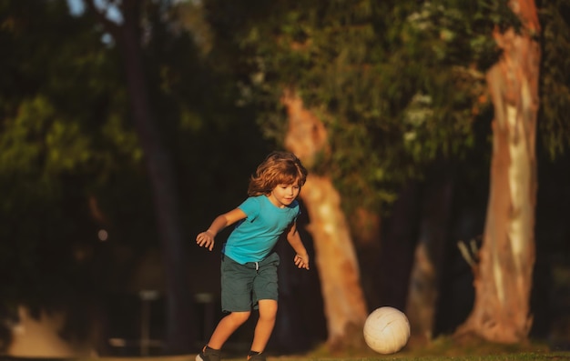 Bambino che calcia il calcio sul campo sportivo durante la partita di calcio Calciatore bambino nel parco