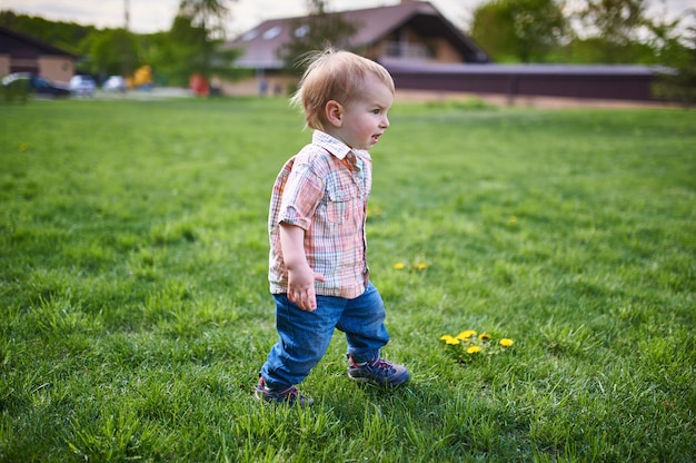 Bambino che cammina sul prato verde al giorno soleggiato