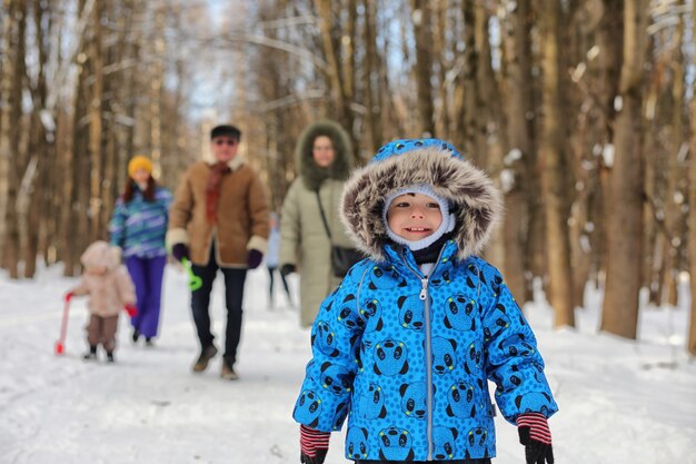 Bambino che corre in un parco invernale e si diverte con la famiglia