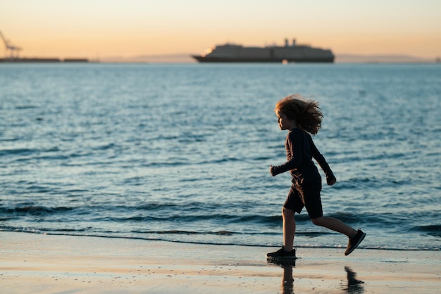 Bambino che corre sulla spiaggia Bambino felice che corre in mare durante le vacanze estive Vacanze estive con il bambino