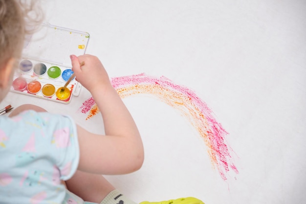 Bambino che dipinge arcobaleno bambina che dipinge arcobaleno colorato su un grande foglio di carta