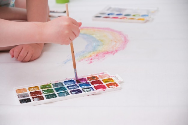 Bambino che dipinge arcobaleno bambina che dipinge arcobaleno colorato su un grande foglio di carta