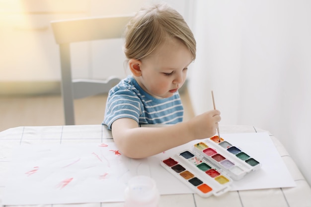 Bambino che dipinge e disegna con pittura ad acquerello a tavola bianca Sviluppo del potenziale creativo