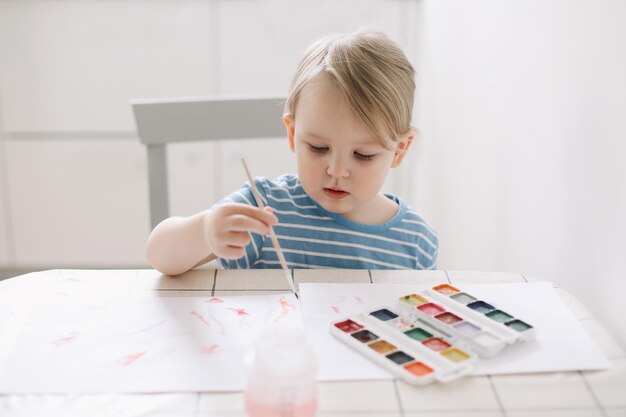 Bambino che dipinge e disegna con pittura ad acquerello a tavola bianca Sviluppo del potenziale creativo