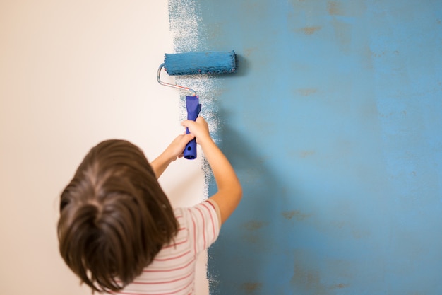 Bambino che dipinge la parete di casa a colori