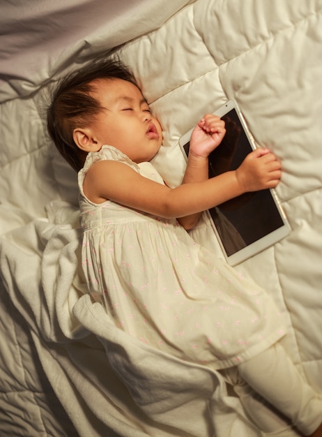 bambino che dorme sul letto dopo aver giocato a tablet