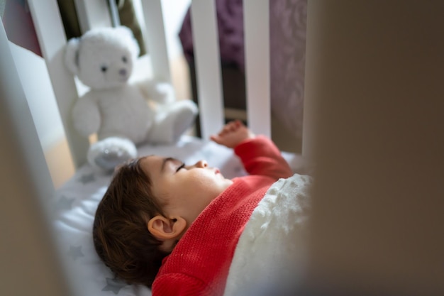 Bambino che fa un pisolino nella culla Un ragazzo caucasico di un anno che riposa sdraiato accanto a un animale farcito