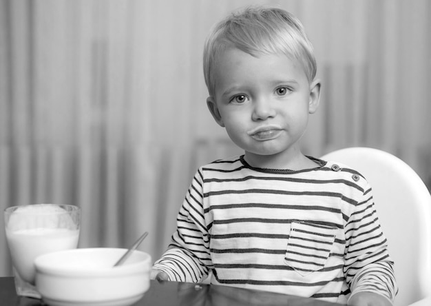 Bambino che fa uno spuntino a casa ragazzo carino che mangia colazione bambino mangia porridge ragazzo carino occhio azzurro