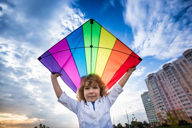 Bambino che fa volare un aquilone contro il drammatico sfondo del cielo blu