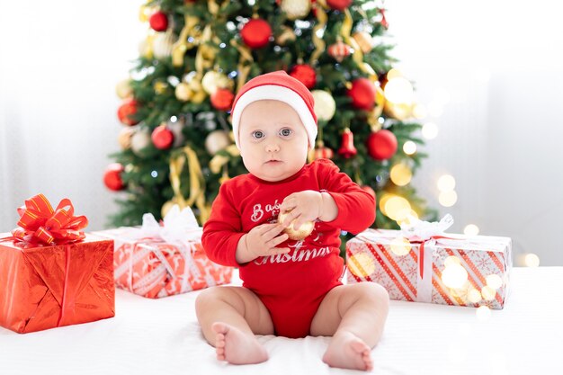 bambino che festeggia il nuovo anno a casa con albero di natale e regali concetto di vacanza buon natale