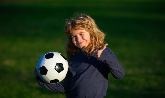 Bambino che gioca a calcio bambino felice che si diverte sport gioco di calcio attività per bambini piccolo giocatore di calcio Ragazzo che tiene il pallone da calcio primo piano ritratto sportivo per bambini