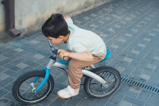 Bambino che gioca a correre in bicicletta nel cortile di casa Bambino in età prescolare all'aperto Famiglia felice infanzia