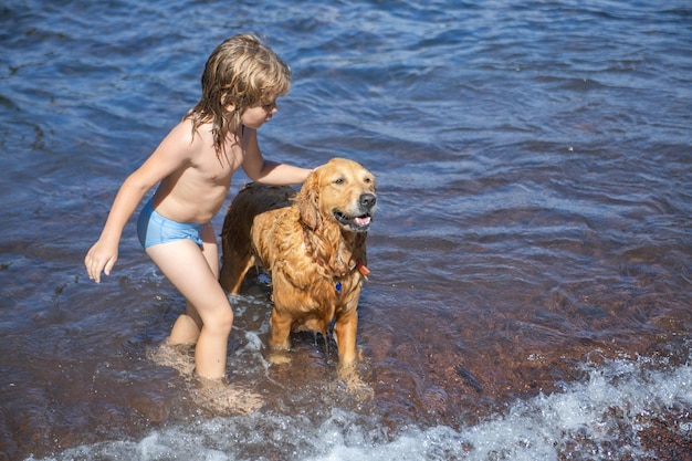 Bambino che gioca con il cane in acqua di mare sulla spiaggia.