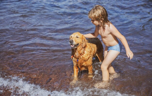 Bambino che gioca con il cane in acqua di mare sulla spiaggia