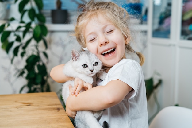 bambino che gioca con il piccolo gatto. la bambina tiene un gattino bianco.