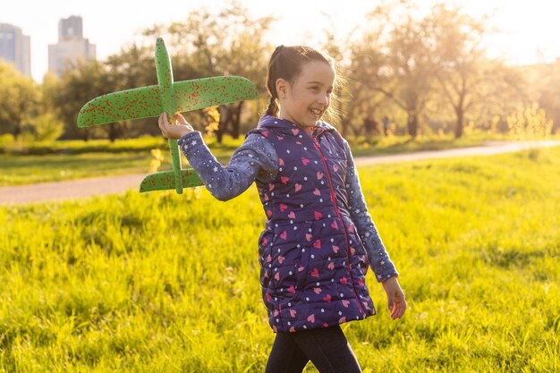 Bambino che gioca con l'aereo. La ragazza felice gioca all'aperto.