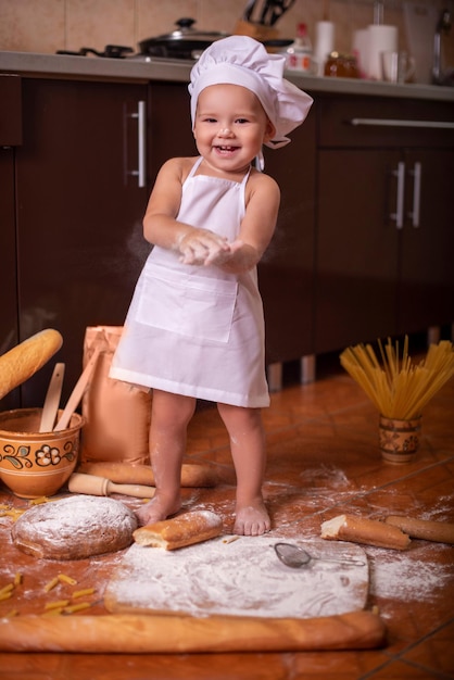 bambino che gioca con la farina in cucina vestito da cuoco