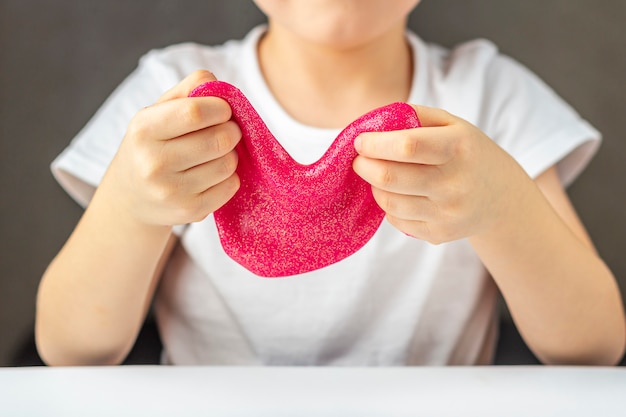 Bambino che gioca con la melma glitter rosa fatta in casa