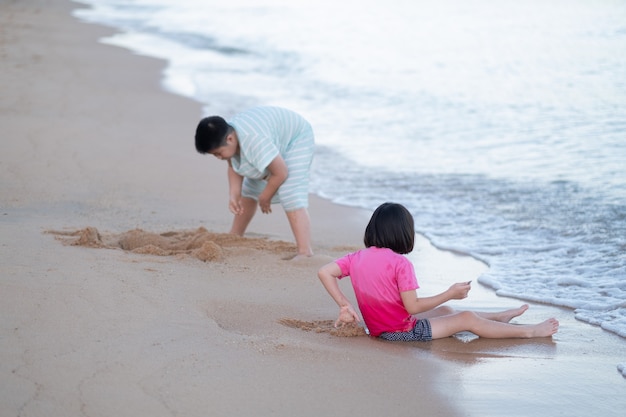 Bambino che gioca con la sabbia sulla spiaggia, bambini che giocano in mare