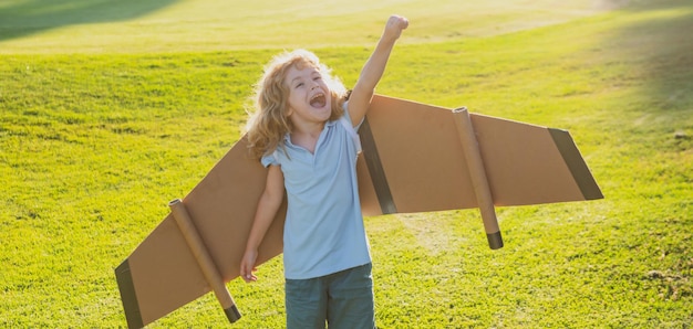 Bambino che gioca con le ali dell'aereo giocattolo nella tecnologia di innovazione del parco estivo e concetto di successo kid pilo