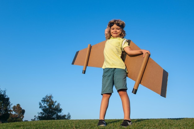 Bambino che gioca con le ali dell'aereo giocattolo nella tecnologia di innovazione del parco estivo e concetto di successo kid pilo