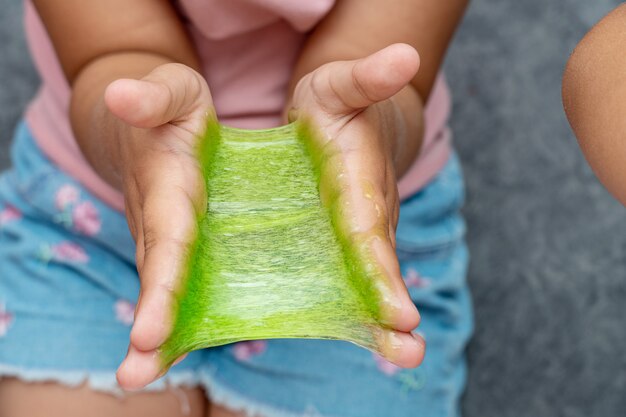 Bambino che gioca con melma di colore rosso, gunge, gel nelle mani