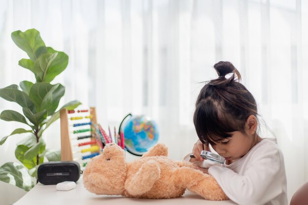 Bambino che gioca con orsacchiotto Bambina asiatica che abbraccia il suo giocattolo preferito Capretto e animale di peluche a casa