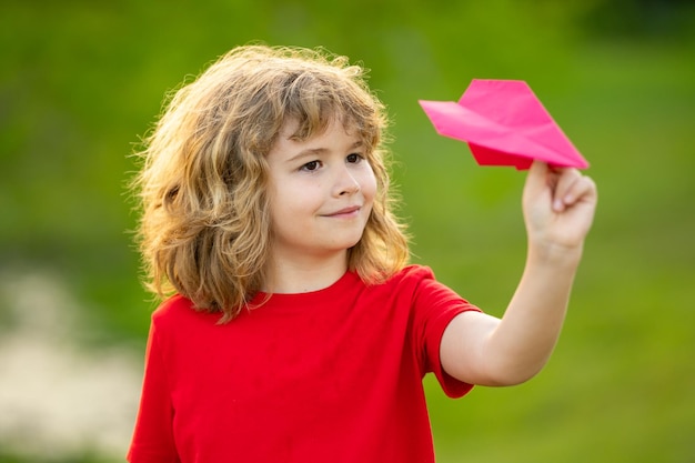 Bambino che gioca con un aereo di carta bambino carino che lancia un aereo da carta nel parco in un giorno d'estate felice ch