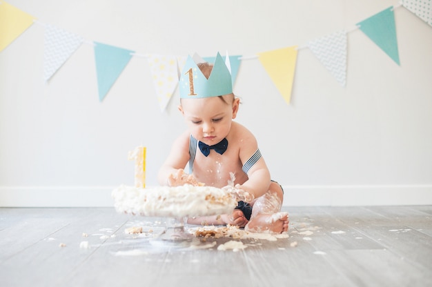 Bambino che gioca con una torta durante la sua festa di compleanno torta smash