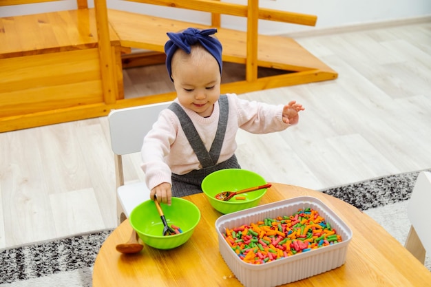 Bambino che gioca gioco sensoriale smistamento pasta colorata