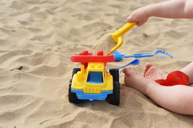 Bambino che gioca sulla sabbia vicino al mare.