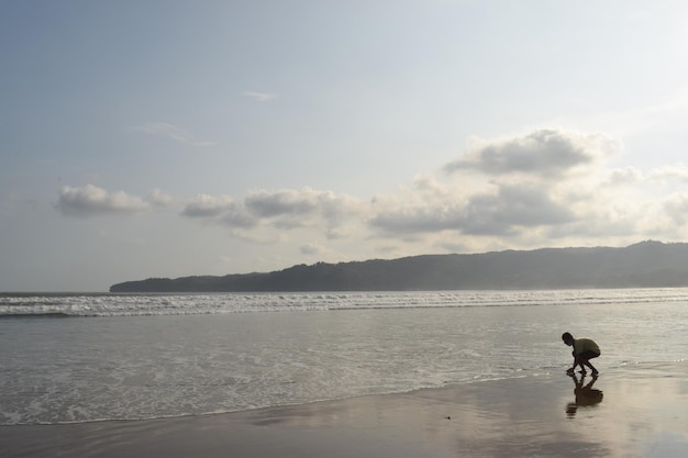 Bambino che gioca sulla spiaggia al tramonto a Pacitan, Indonesia