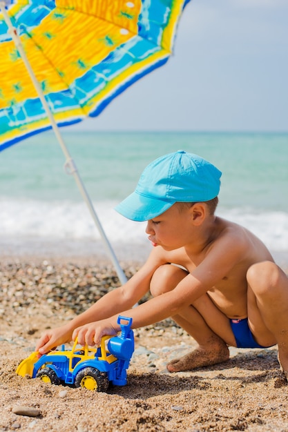 Bambino che gioca sulla spiaggia con la sabbia