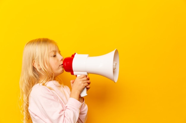 Bambino che grida tramite il megafono. Concetto di comunicazione. sfondo giallo come copia spazio per il testo.