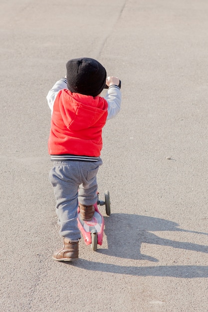 Bambino che guida un piccolo scooter all'aperto