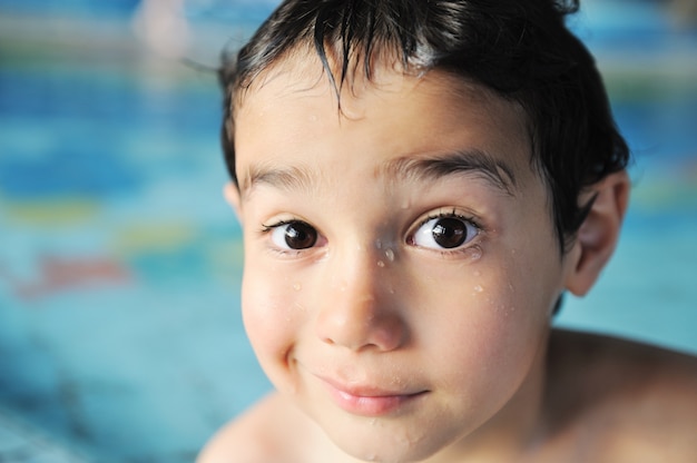 Bambino che ha tempo felice nell&#39;acqua della piscina